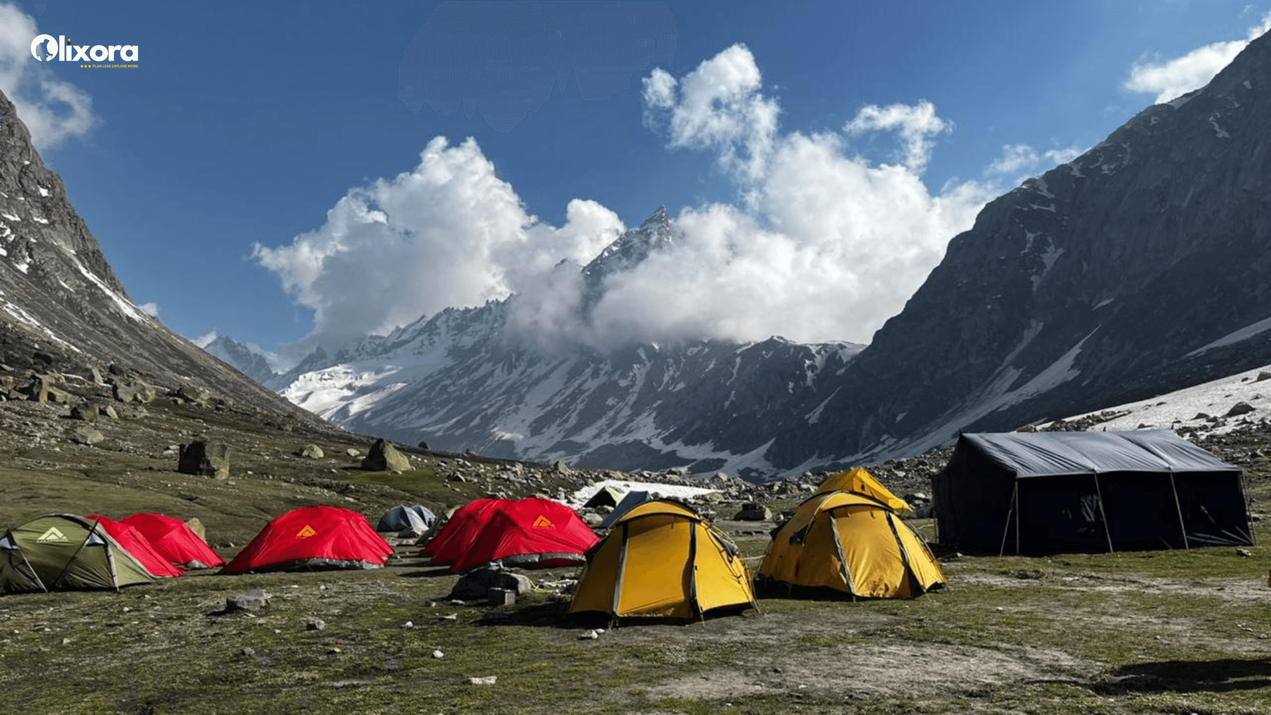 Colorful adventure tents pitched on the rocky, snow-fringed clearing of Balu ka Ghera campsite under a clear blue sky